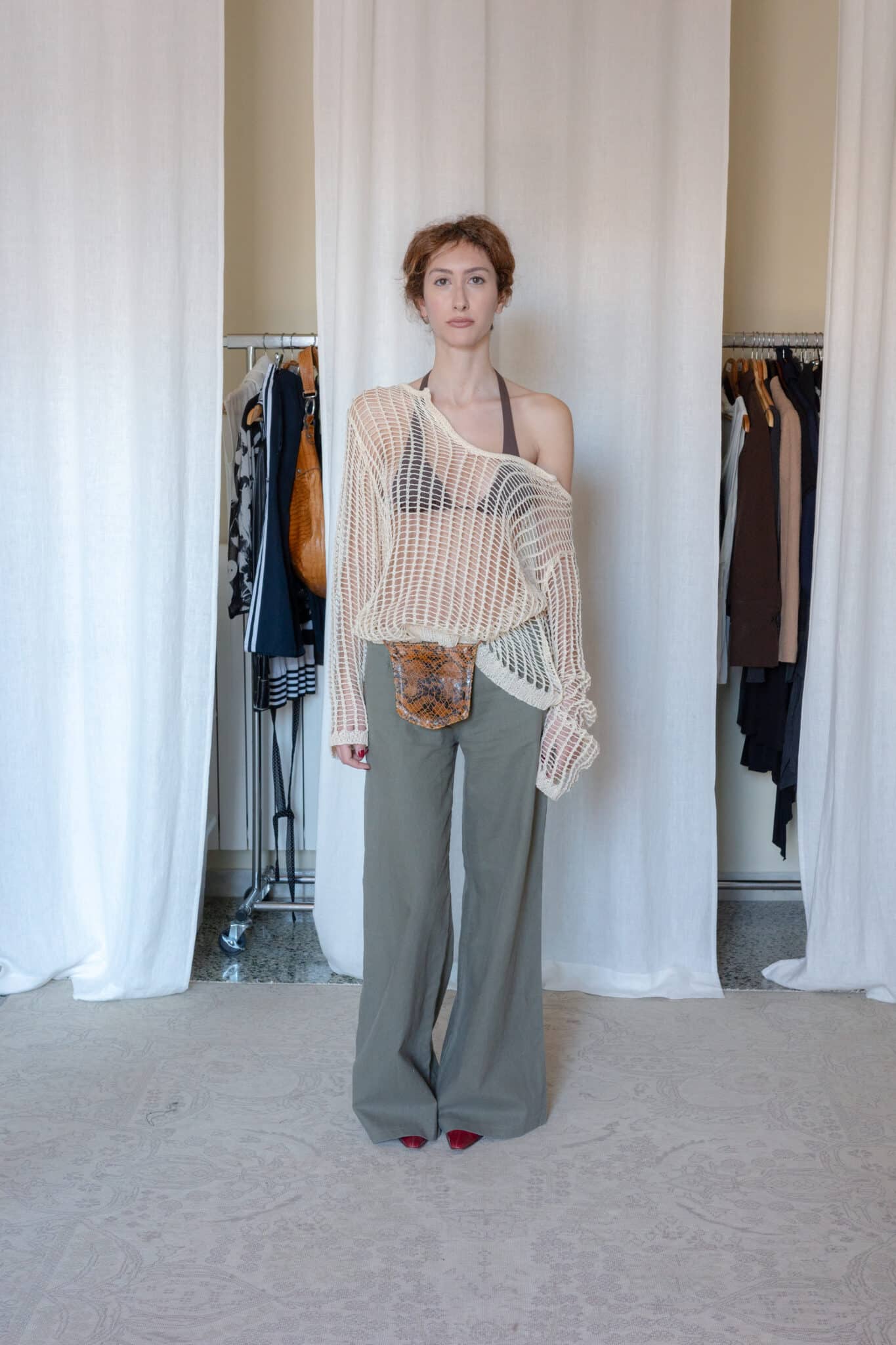 Sheer open knit sweater styled with olive wide leg trousers, snakeskin belt bag and red pointed heels