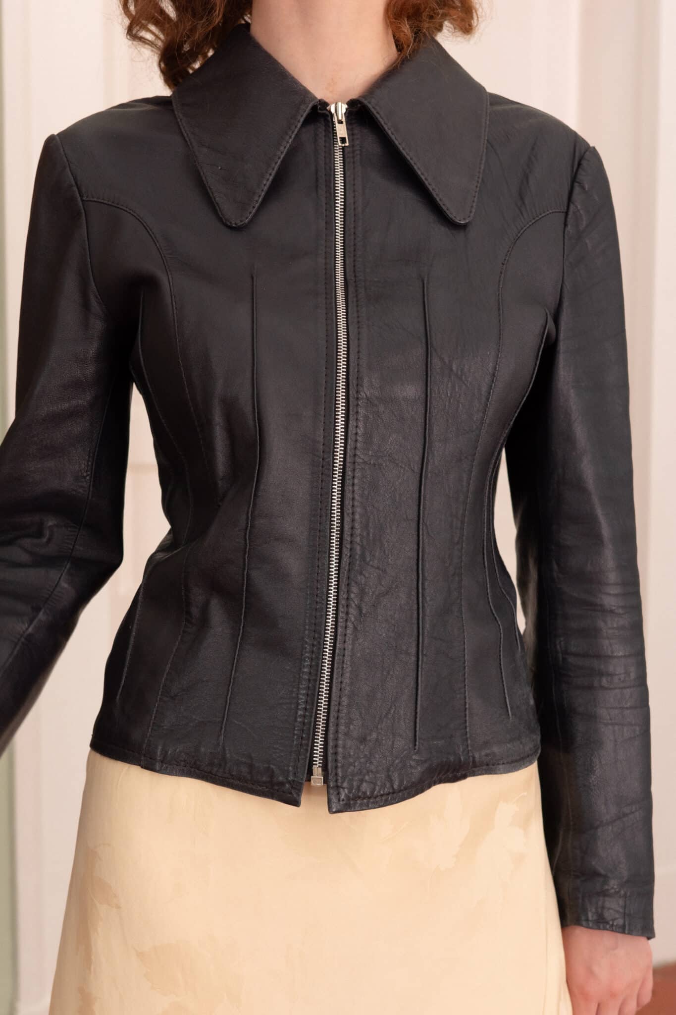 Slim-fit leather jacket in black with a structured collar and clean minimalist design.