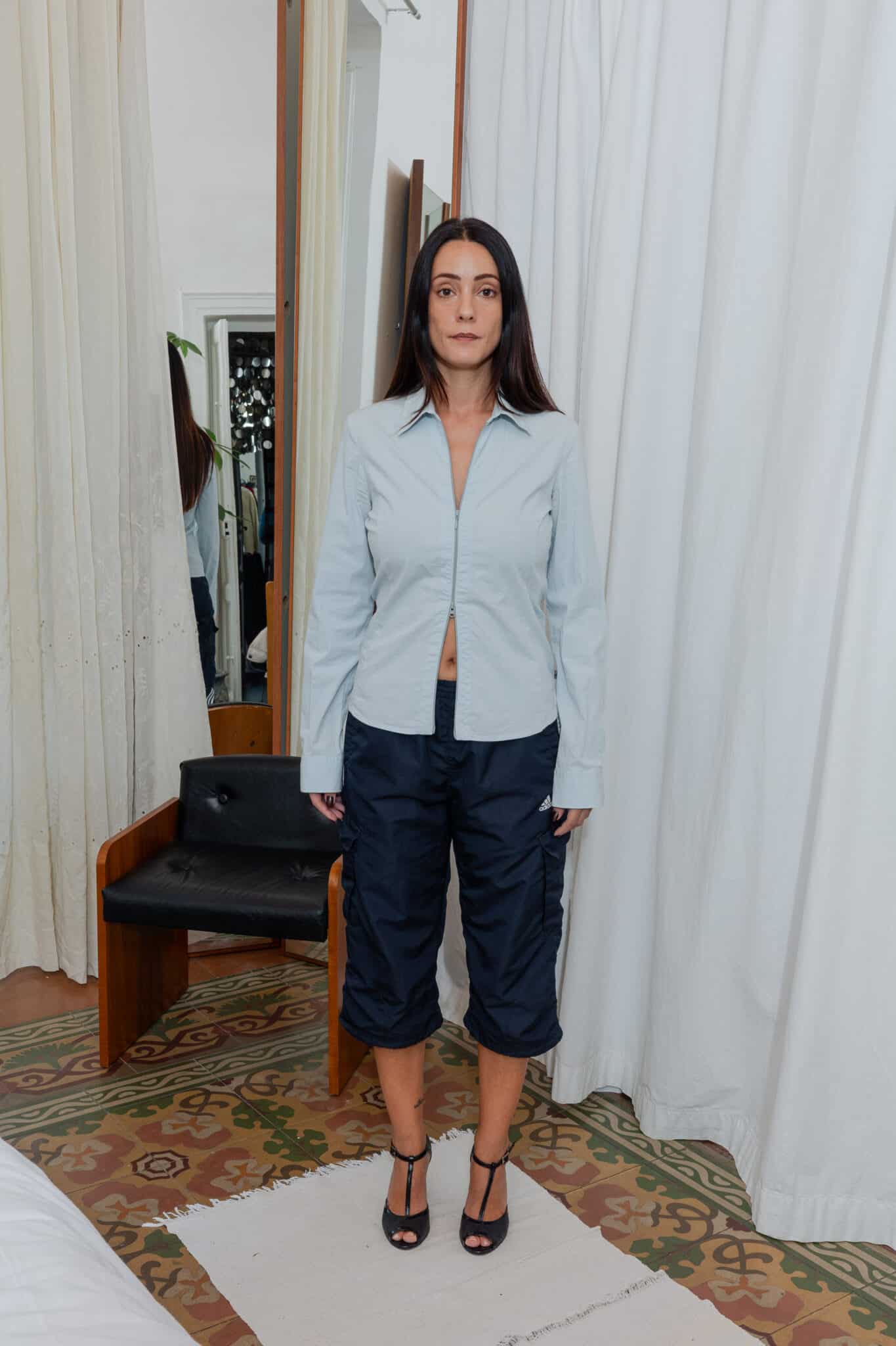 Front view of light blue zip shirt paired with navy Adidas capris and heeled shoes.