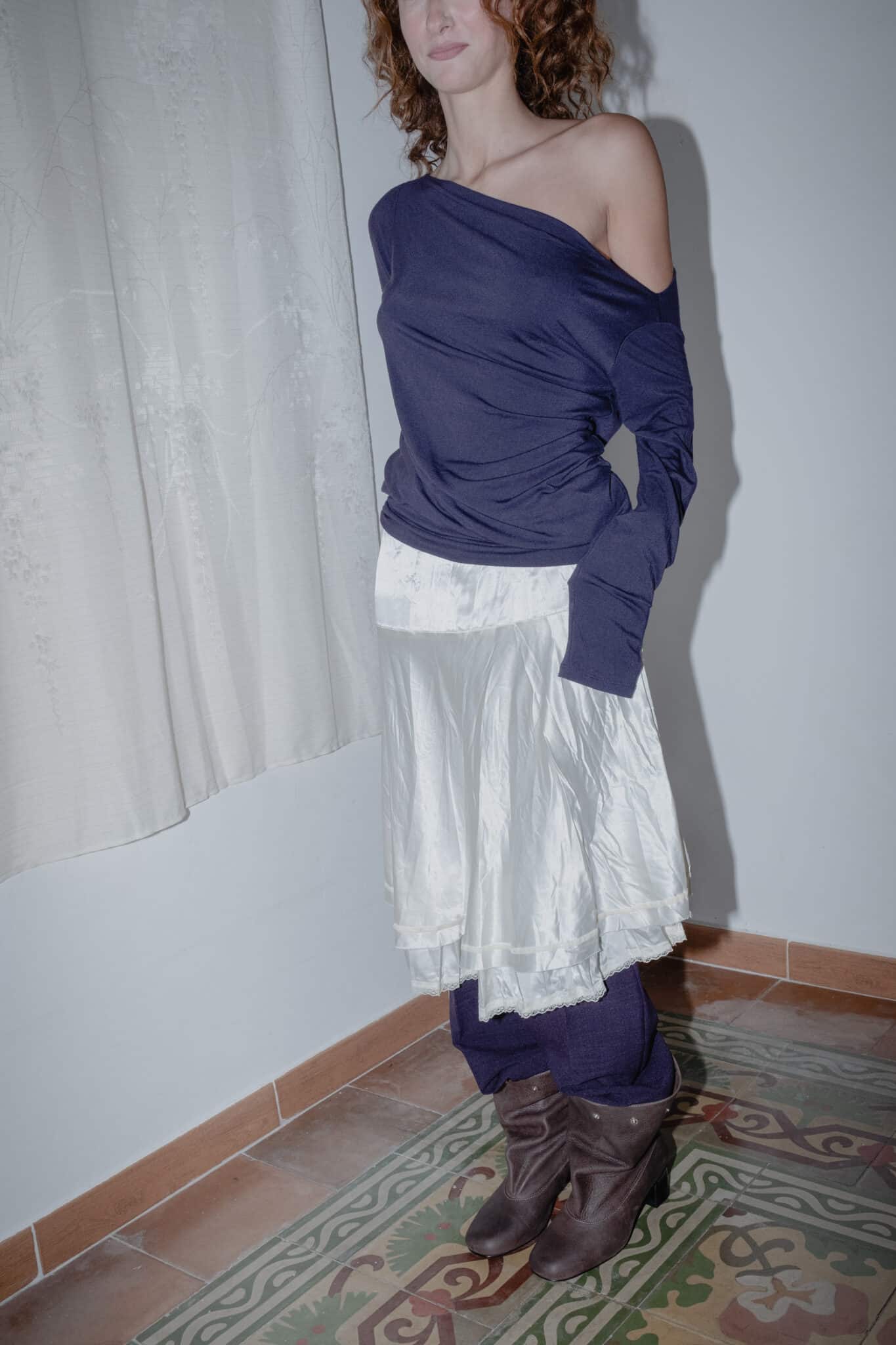 Silk-effect midi skirt paired with a long-sleeved off-shoulder top, creating a soft draped silhouette.