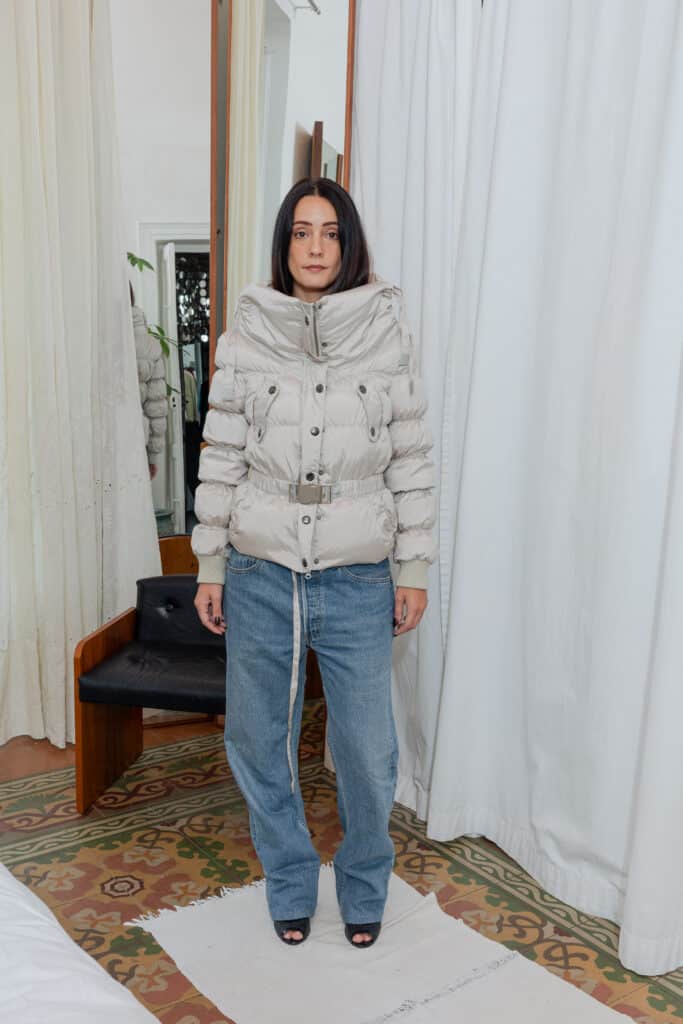 Front view of outfit featuring beige padded jacket styled with Levi’s jeans and open heels.