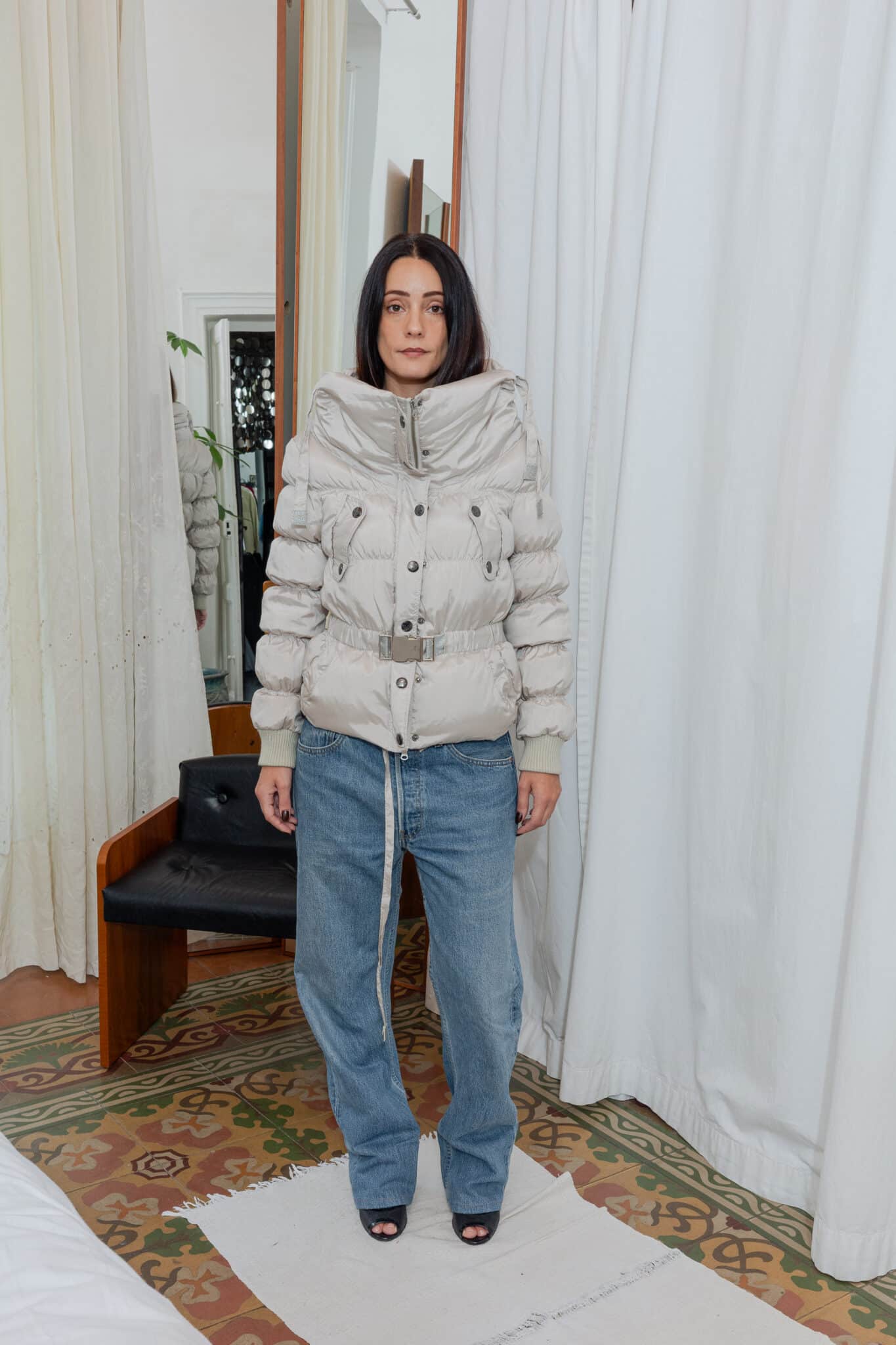 Front view of outfit featuring beige padded jacket styled with Levi’s jeans and open heels.