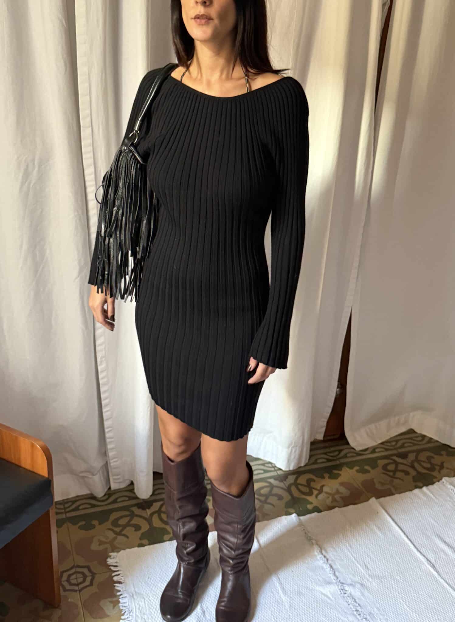 Black ribbed knit mini dress photographed in natural indoor light showing fine texture.