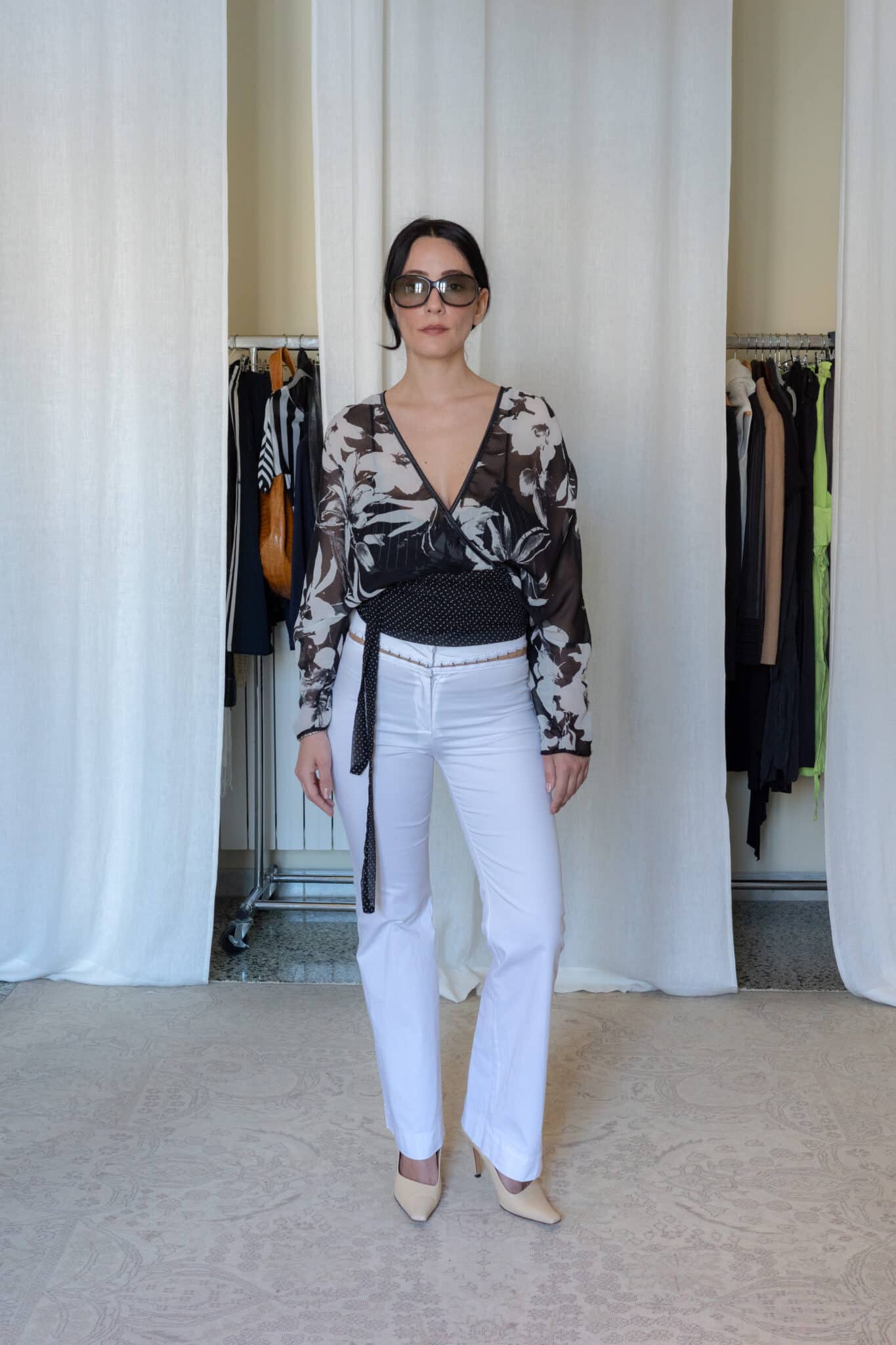 Black sheer floral wrap top with long sleeves styled with white tailored trousers and beige heels, women’s fitted outfit