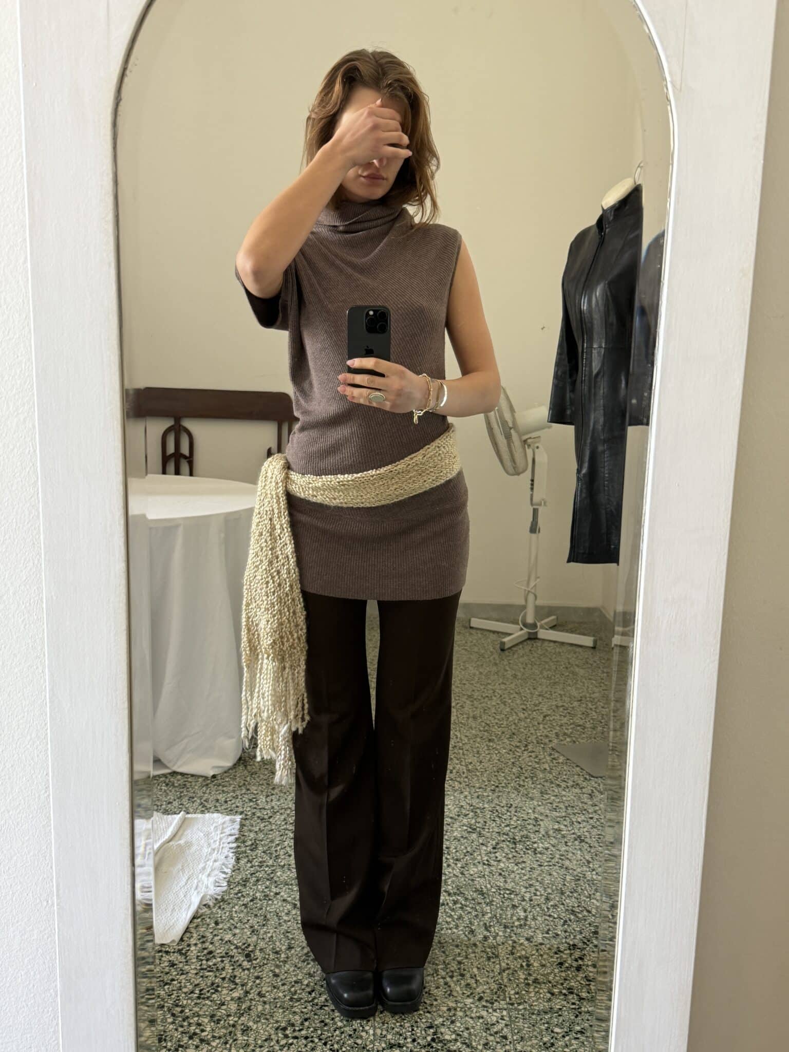 Brown asymmetrical sleeveless knit top with draped neckline and fitted silhouette