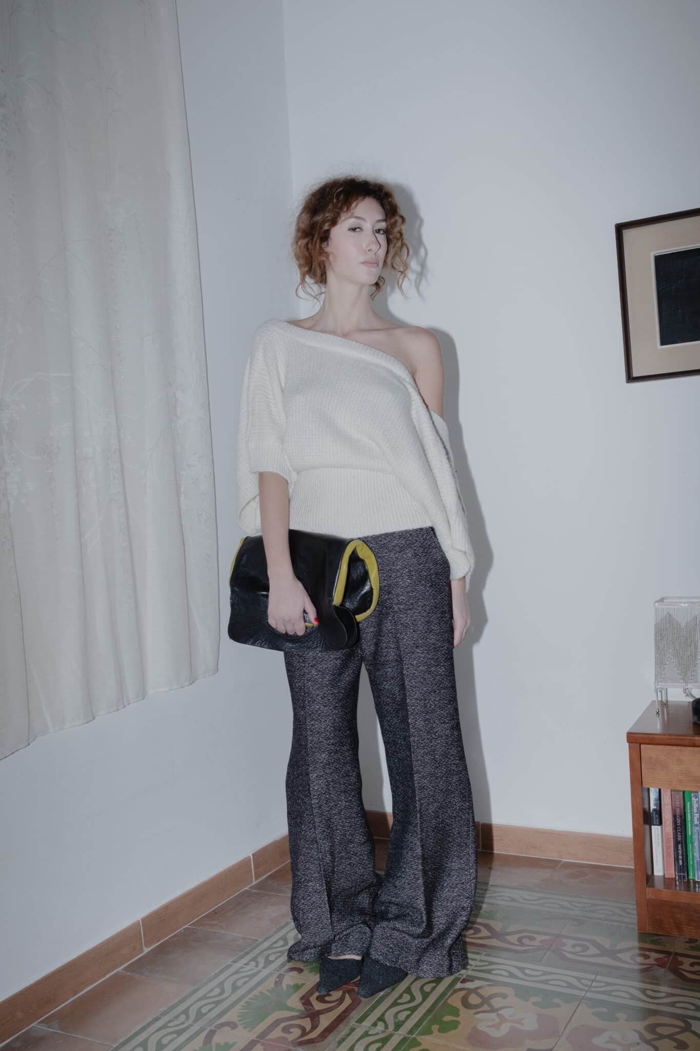 outfit consisting of an off-shoulder cream sweater and structured heather-grey trousers.
