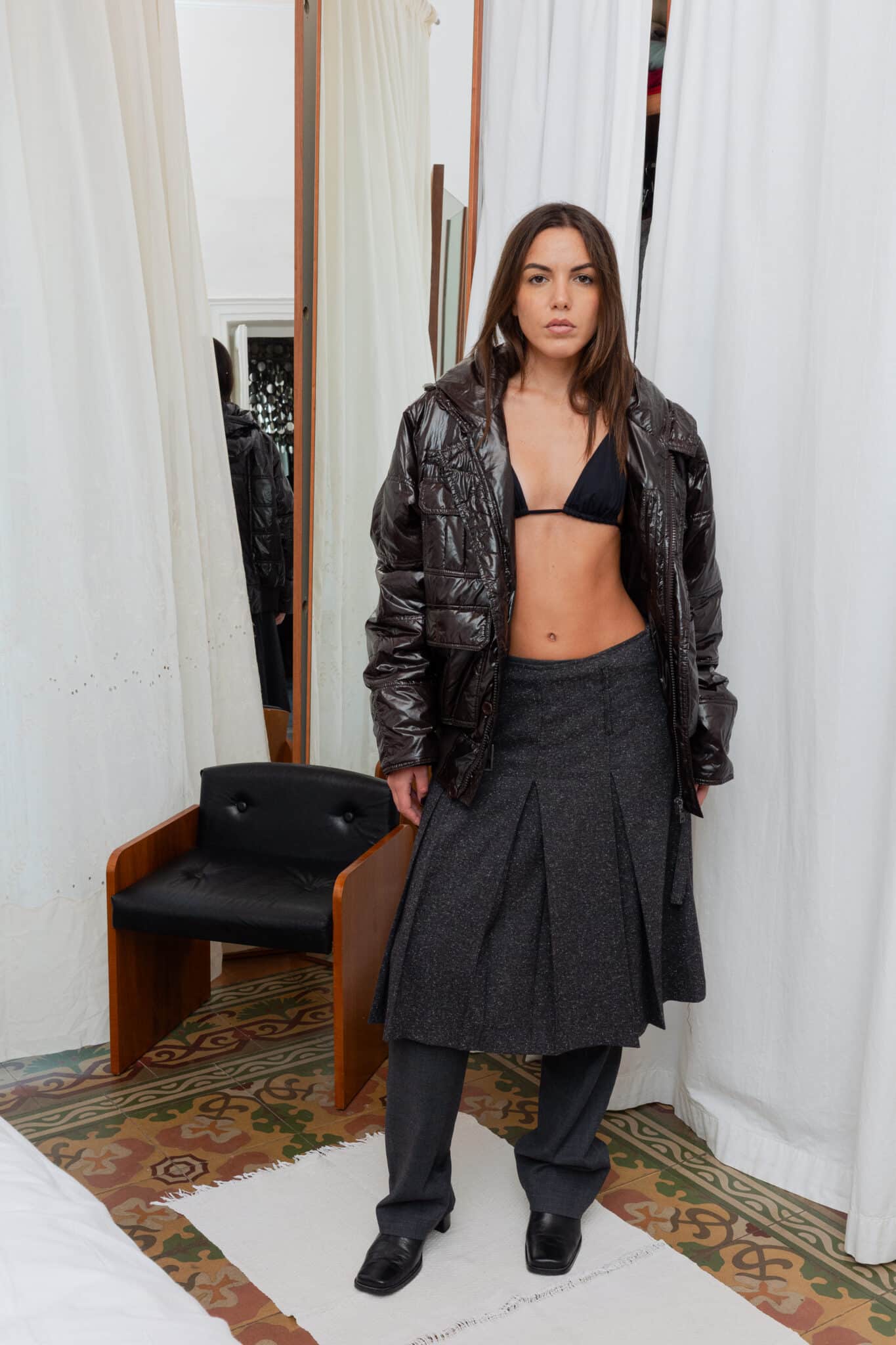 Charcoal pleated wool skirt layered over tailored trousers.