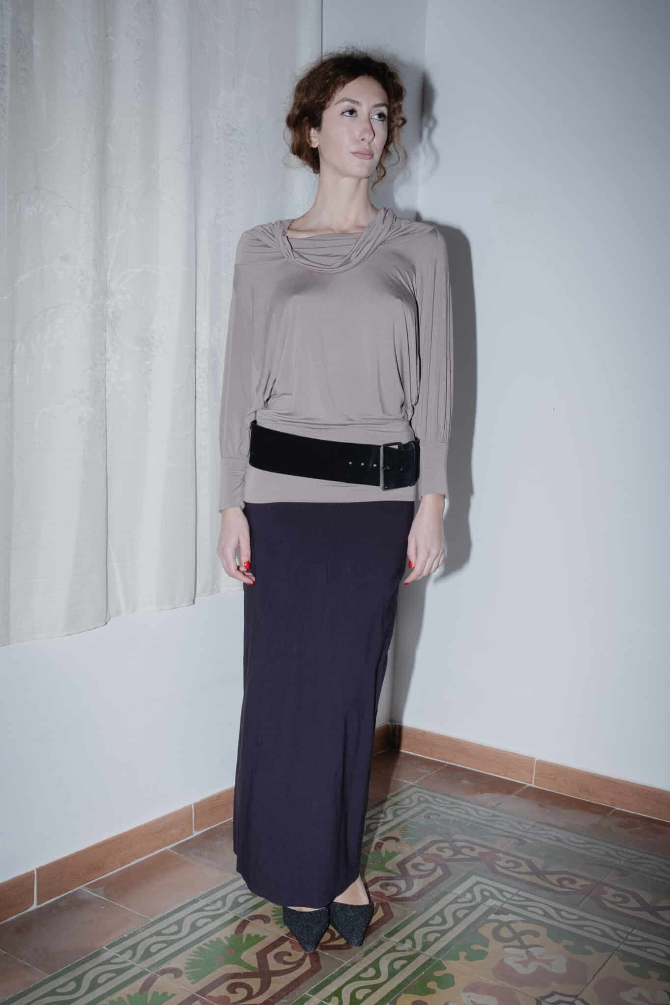 taupe draped long-sleeve top paired with a navy maxi skirt and wide suede belt.