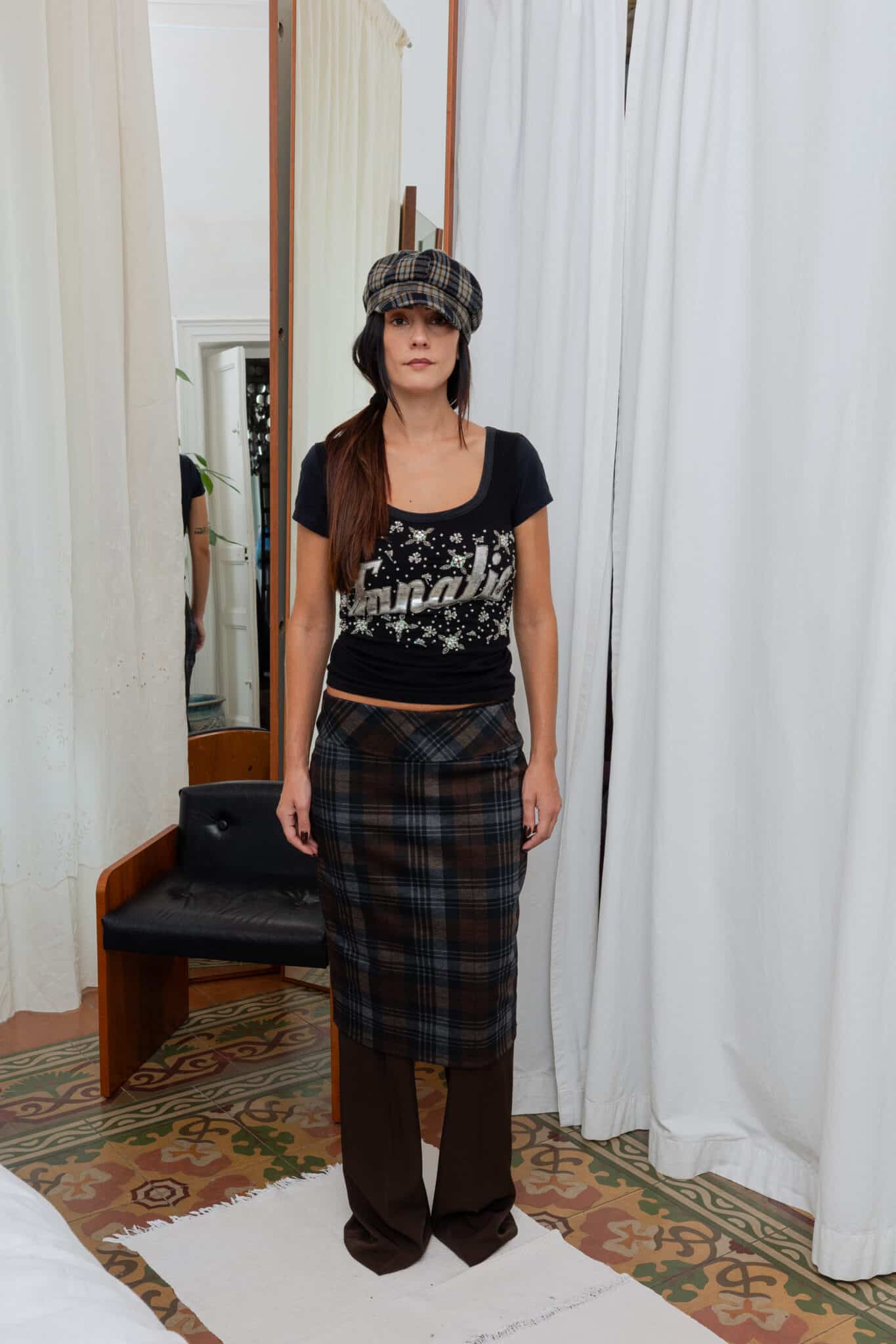 Full outfit featuring plaid skirt layered over brown trousers with a fitted graphic t-shirt.