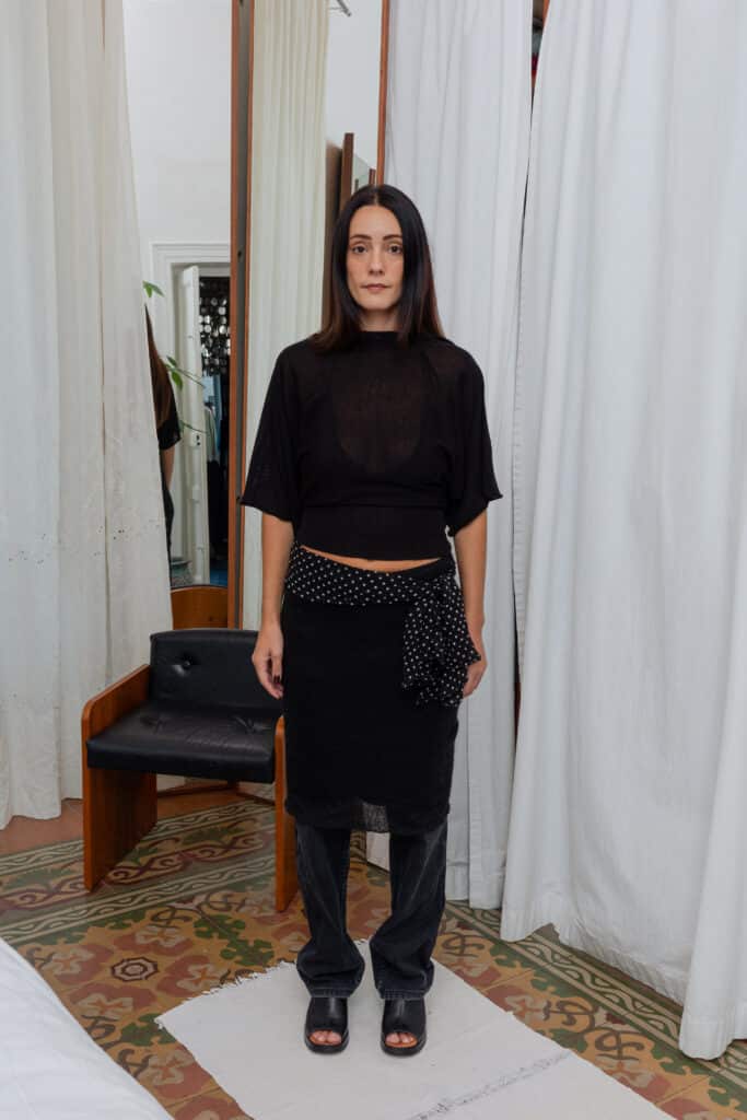Full outfit featuring sheer black top, black textured skirt, and polka dot scarf detail.